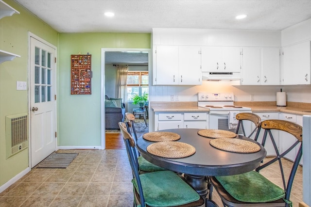 kitchen with a textured ceiling, white cabinets, white range oven, ventilation hood, and light tile floors