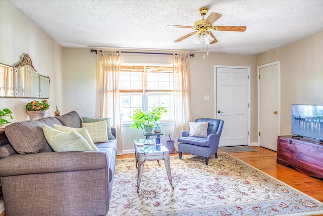 living room with ceiling fan, light hardwood / wood-style flooring, and a textured ceiling