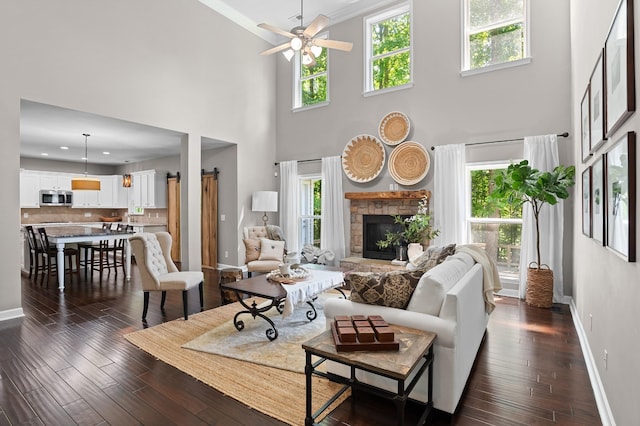 living room with ceiling fan, dark hardwood / wood-style flooring, and a stone fireplace