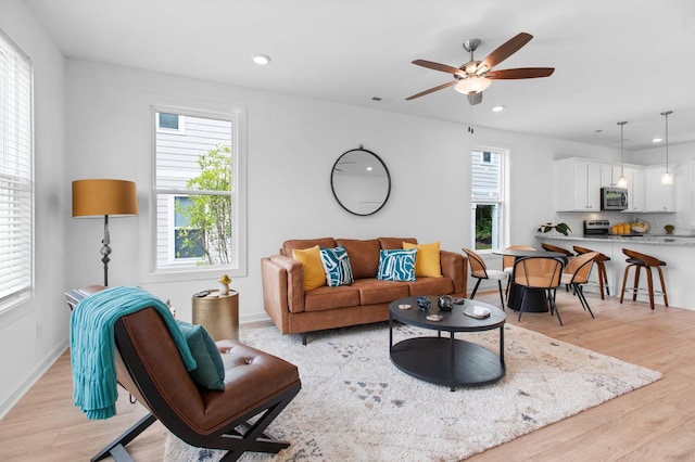 living room featuring plenty of natural light, ceiling fan, and light hardwood / wood-style flooring