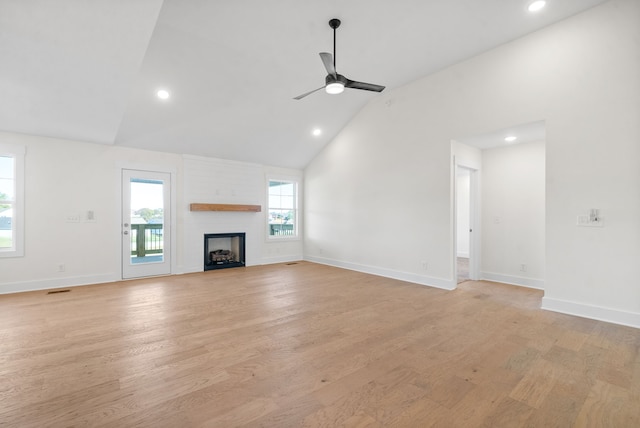 unfurnished living room with ceiling fan, high vaulted ceiling, a fireplace, and light hardwood / wood-style floors