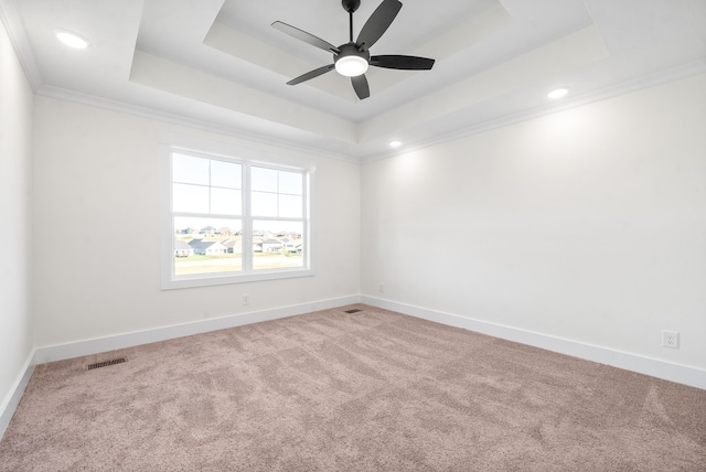 carpeted empty room featuring a raised ceiling, ornamental molding, and ceiling fan