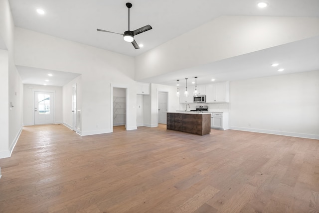 unfurnished living room with high vaulted ceiling, sink, ceiling fan, and light hardwood / wood-style floors