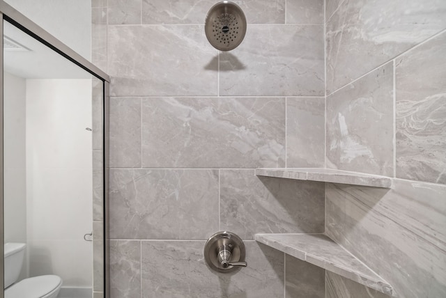 bathroom with tiled shower and toilet