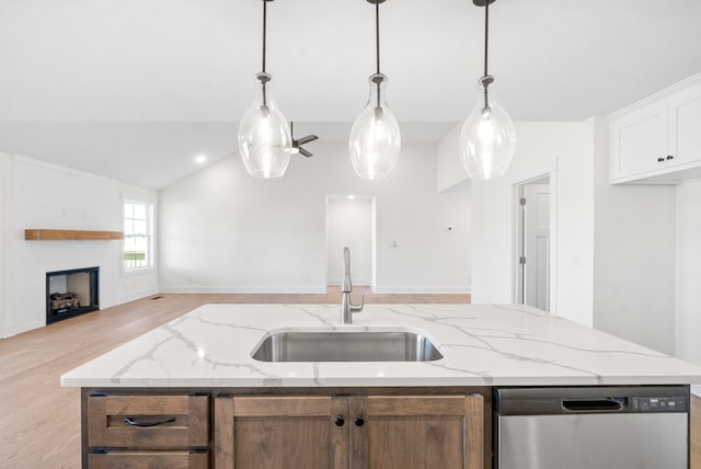 kitchen featuring sink, dishwasher, an island with sink, a large fireplace, and white cabinets