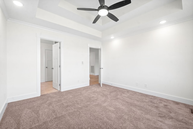 unfurnished bedroom featuring crown molding, light colored carpet, ceiling fan, and a tray ceiling