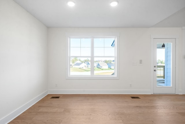 empty room with light hardwood / wood-style floors and a healthy amount of sunlight