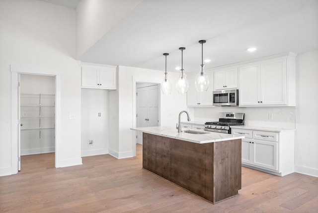 kitchen featuring stainless steel appliances, white cabinetry, a kitchen island with sink, and decorative light fixtures