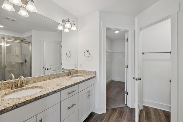 bathroom with hardwood / wood-style floors, dual bowl vanity, and an enclosed shower