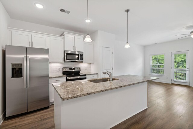 kitchen with appliances with stainless steel finishes, decorative backsplash, dark hardwood / wood-style floors, sink, and a kitchen island with sink