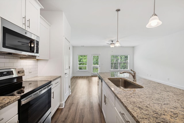 kitchen featuring appliances with stainless steel finishes, light stone countertops, backsplash, sink, and white cabinetry