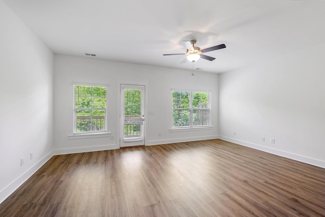 empty room featuring ceiling fan, plenty of natural light, and dark hardwood / wood-style flooring