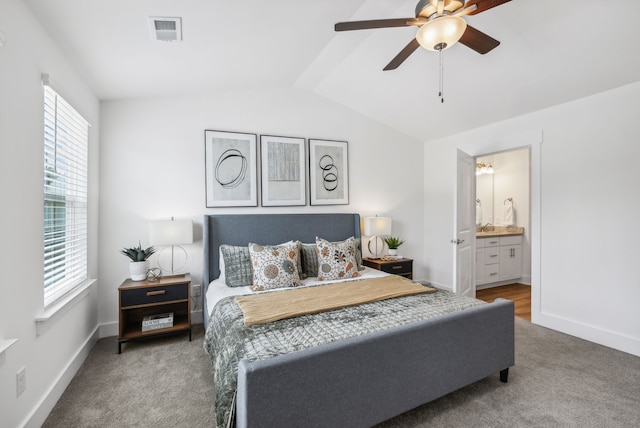 carpeted bedroom featuring ceiling fan, vaulted ceiling, and ensuite bath