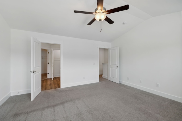 unfurnished bedroom featuring ceiling fan, carpet flooring, and vaulted ceiling