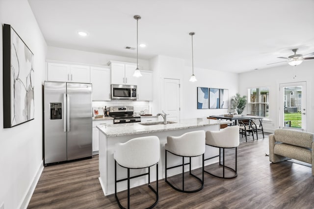 kitchen with backsplash, dark hardwood / wood-style flooring, appliances with stainless steel finishes, light stone countertops, and white cabinets