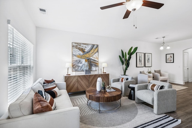 living room with ceiling fan with notable chandelier and dark wood-type flooring