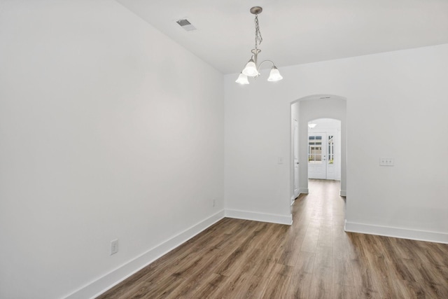 unfurnished dining area featuring a notable chandelier and wood-type flooring