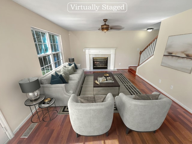 living room with a tile fireplace, dark hardwood / wood-style flooring, and ceiling fan