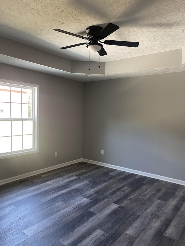 empty room with dark wood-style flooring, a textured ceiling, and baseboards
