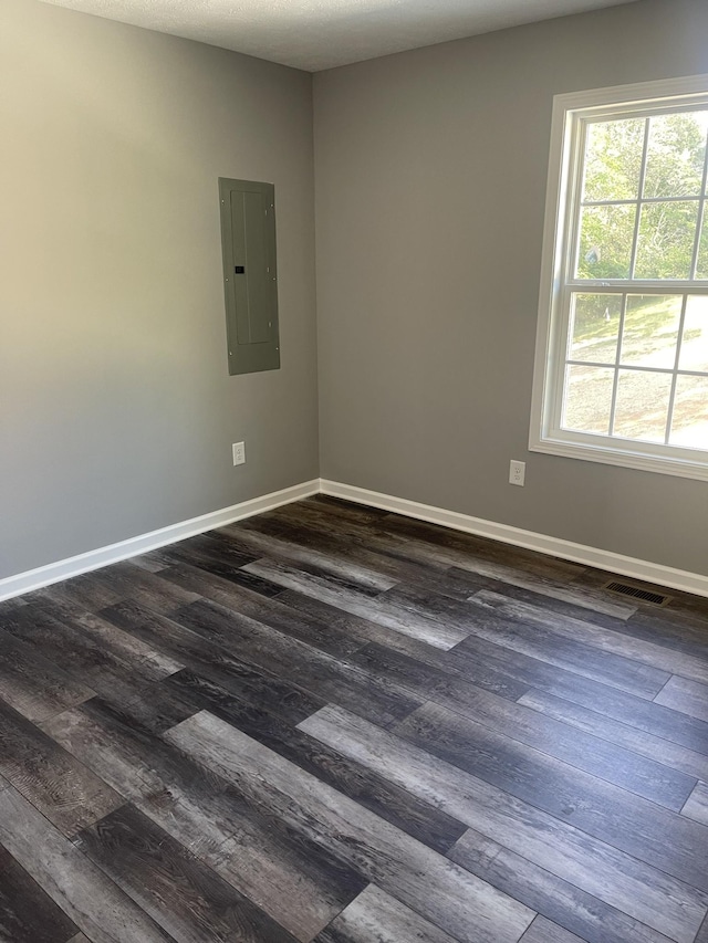 unfurnished room featuring electric panel, dark wood-type flooring, and baseboards