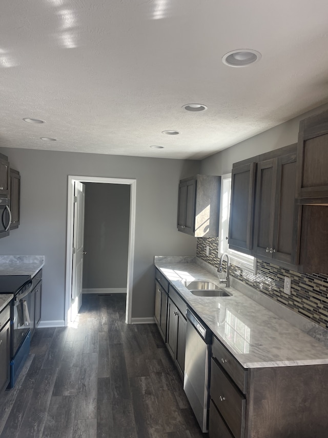 kitchen with sink, appliances with stainless steel finishes, tasteful backsplash, dark brown cabinetry, and dark wood-type flooring