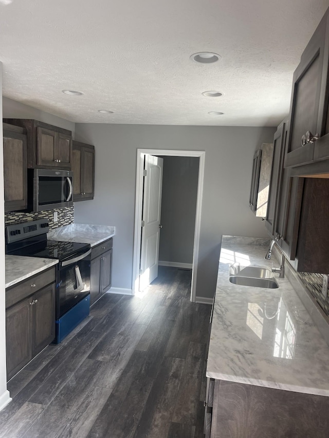 kitchen featuring a sink, dark brown cabinetry, dark wood finished floors, and appliances with stainless steel finishes
