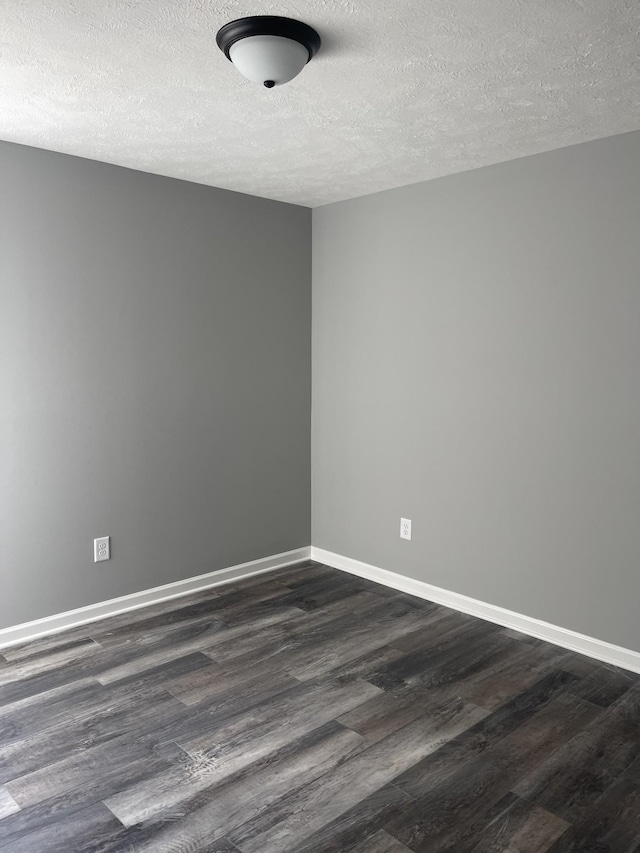 empty room with baseboards, dark wood-style flooring, and a textured ceiling