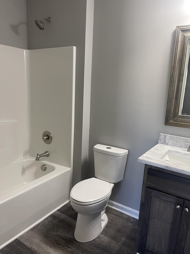 full bath featuring toilet, wood finished floors, shower / bath combination, baseboards, and vanity
