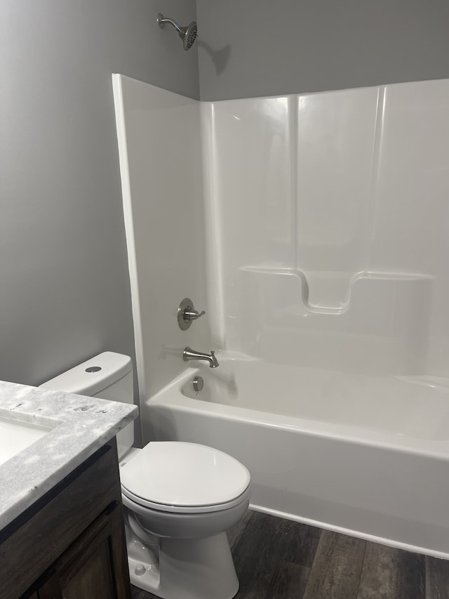 full bathroom featuring wood-type flooring, bathing tub / shower combination, vanity, and toilet