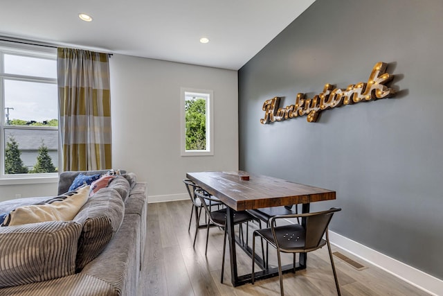 dining space featuring hardwood / wood-style floors and vaulted ceiling