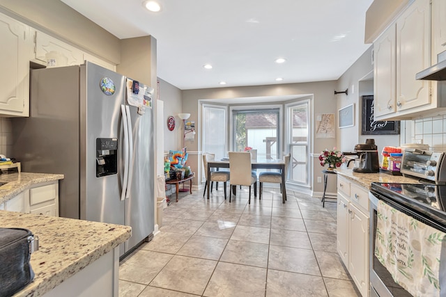 kitchen featuring stainless steel appliances, light stone counters, tasteful backsplash, and light tile flooring