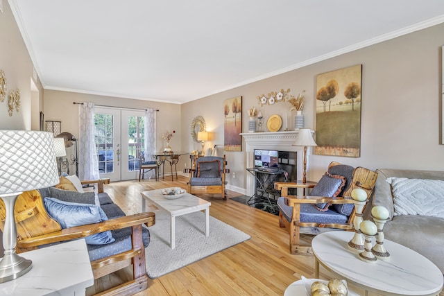 living room featuring light hardwood / wood-style floors, french doors, a tile fireplace, and crown molding