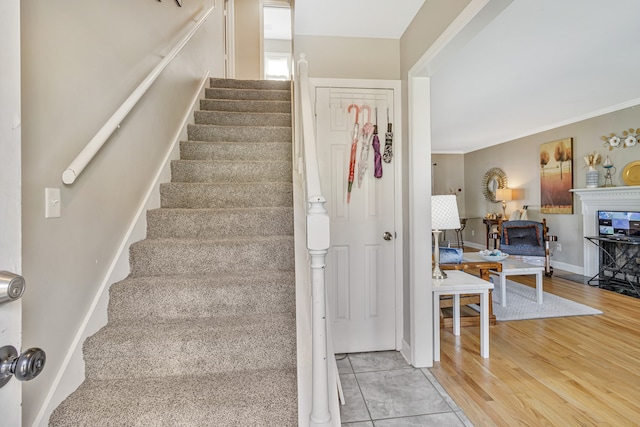 staircase featuring crown molding and light hardwood / wood-style flooring