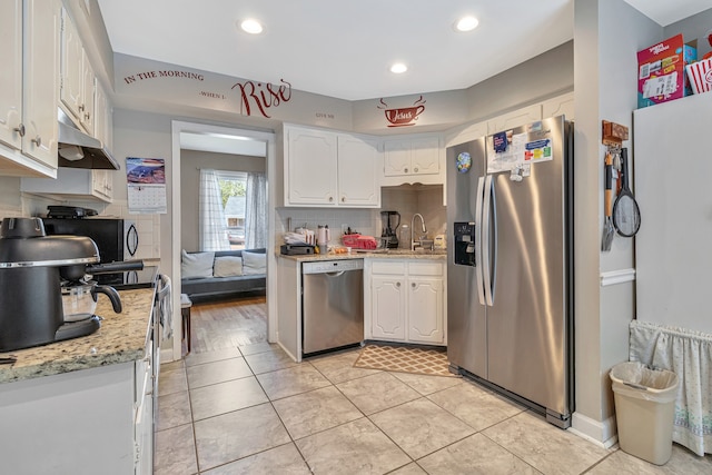 kitchen with light stone countertops, light hardwood / wood-style floors, backsplash, white cabinets, and appliances with stainless steel finishes