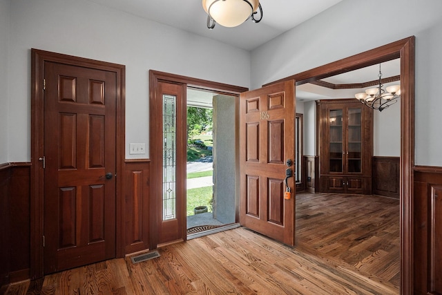 foyer entrance with light wood-type flooring and an inviting chandelier