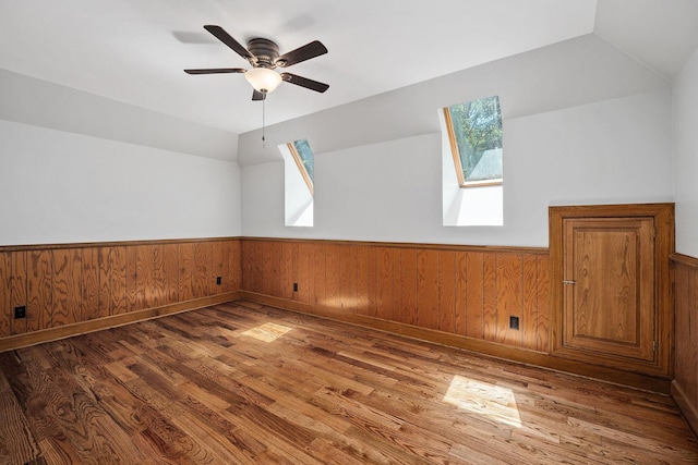 bonus room with vaulted ceiling with skylight, ceiling fan, and dark hardwood / wood-style floors