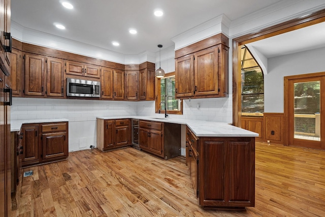 kitchen featuring sink, light hardwood / wood-style flooring, backsplash, crown molding, and pendant lighting