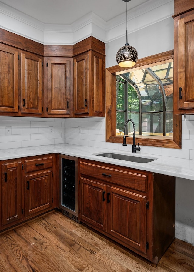 kitchen featuring pendant lighting, sink, beverage cooler, and tasteful backsplash