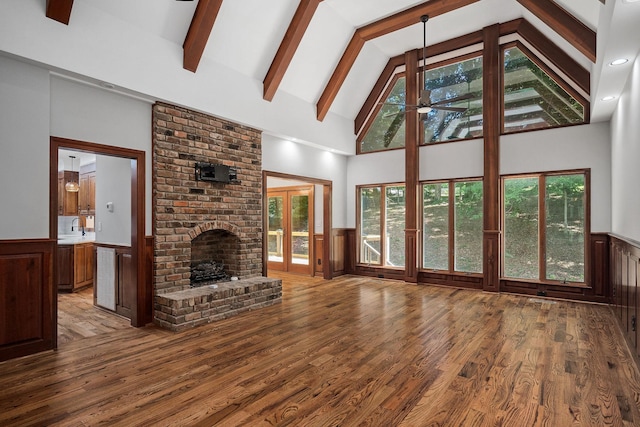 unfurnished living room featuring a brick fireplace, light wood-type flooring, high vaulted ceiling, and ceiling fan