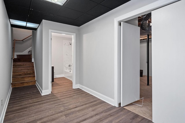 hall featuring wood-type flooring and a paneled ceiling