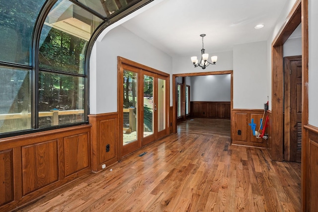 interior space featuring wood-type flooring, french doors, and an inviting chandelier