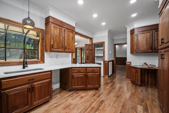 kitchen featuring sink, hanging light fixtures, crown molding, wood-type flooring, and decorative backsplash