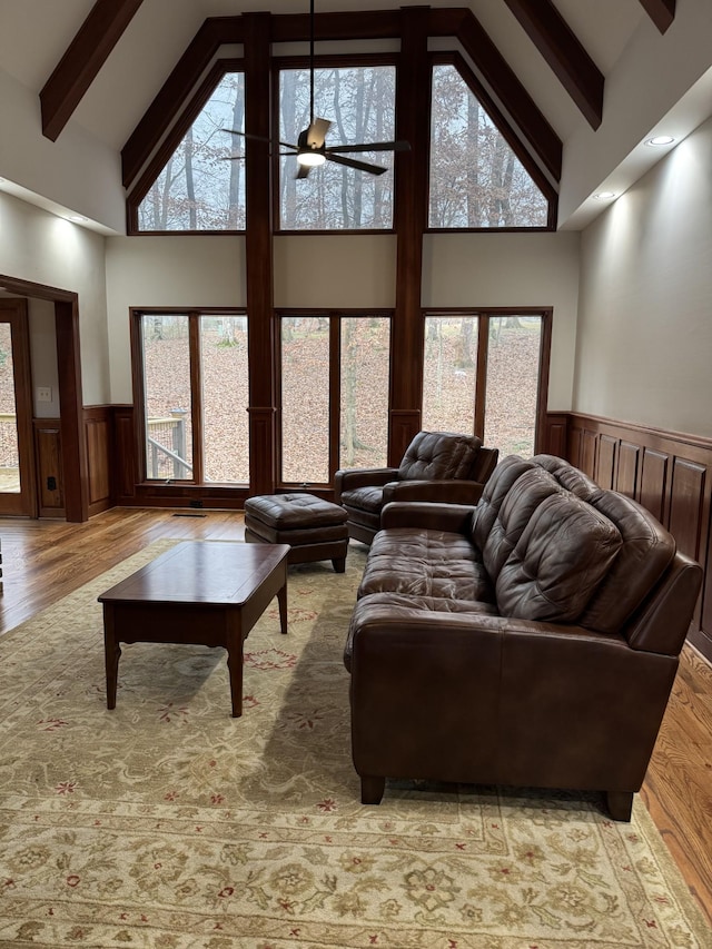 living room featuring beamed ceiling, light hardwood / wood-style flooring, high vaulted ceiling, and ceiling fan