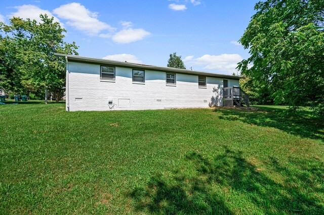 back of house featuring a lawn and a wooden deck