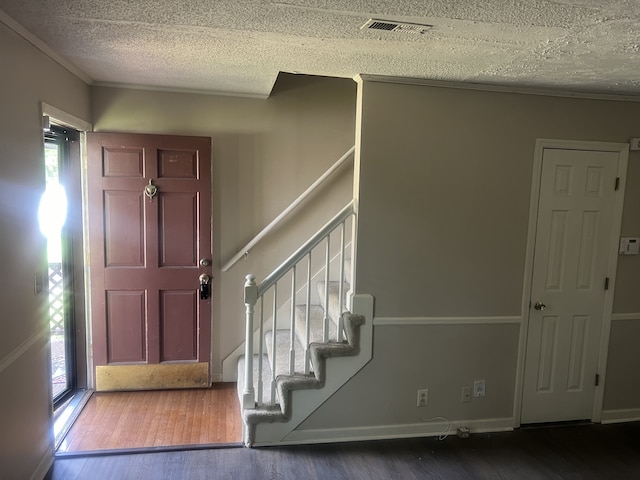 entrance foyer featuring hardwood / wood-style floors, a textured ceiling, and ornamental molding