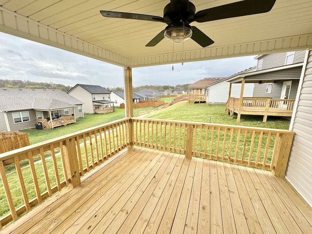 wooden terrace featuring ceiling fan and a yard