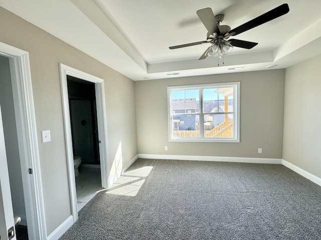 carpeted spare room with a tray ceiling and ceiling fan