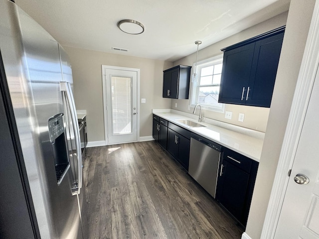 kitchen featuring sink, stainless steel appliances, dark hardwood / wood-style floors, blue cabinets, and decorative light fixtures