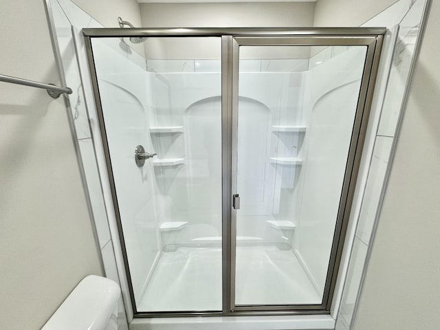 bathroom with a shower with door and toilet