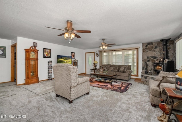 carpeted living room featuring ceiling fan, a textured ceiling, and a wood stove